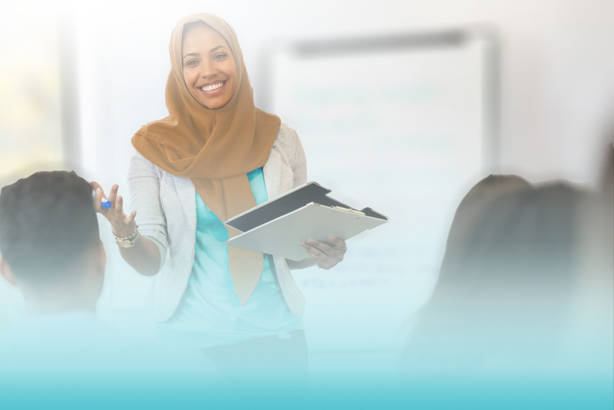 A mid adult Muslim businesswoman smiles as she speaks to a group of employees during a training class.
